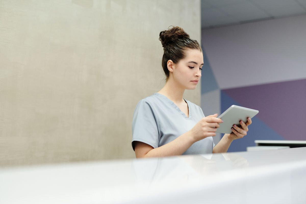 Mitarbeiterin einer Physiotherapiepraxis arbeitet digital mit einem Tablet